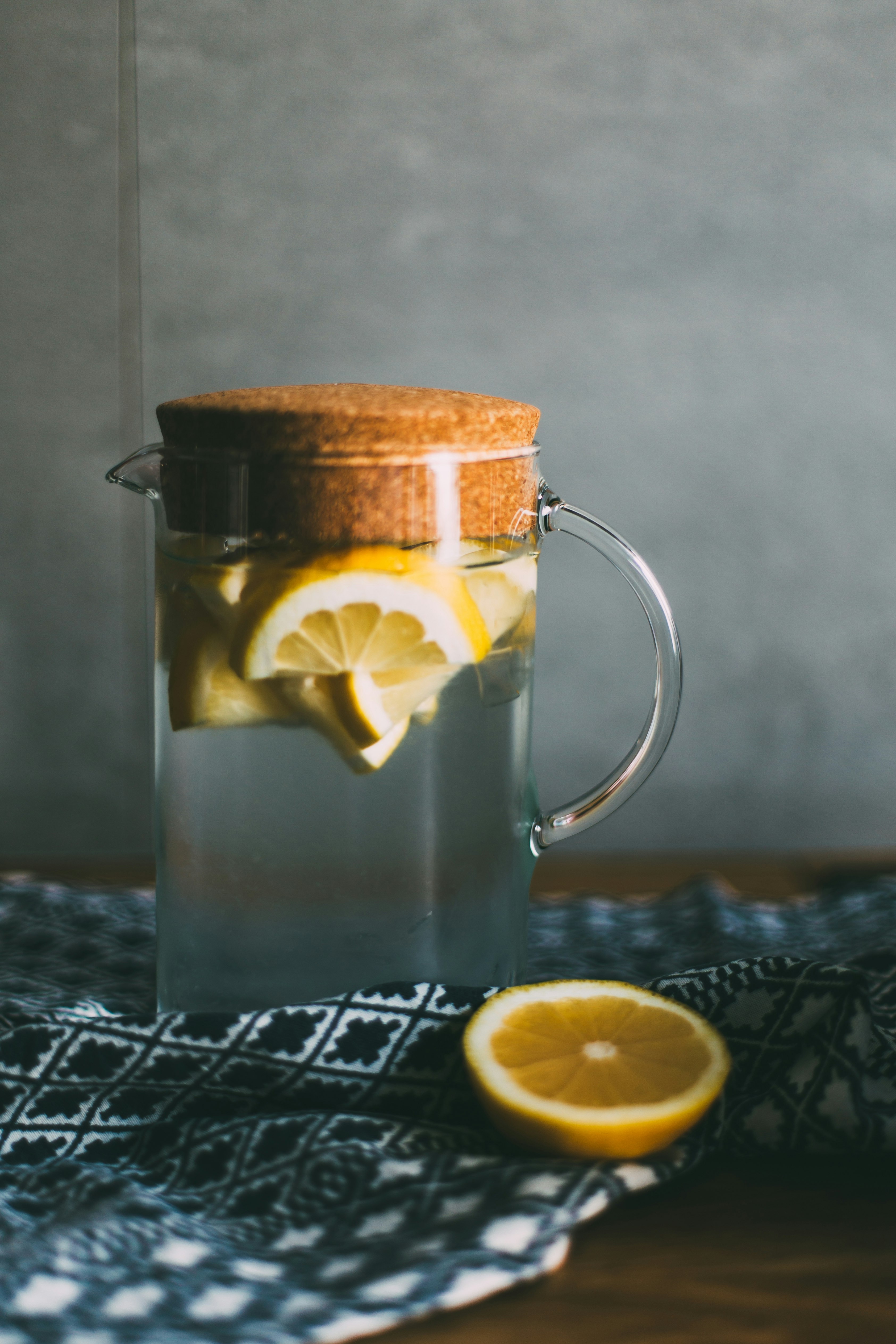 clear glass pitcher filled with sliced lemons on black and white table runner